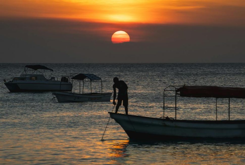 fisherman standing on a boat at sunset