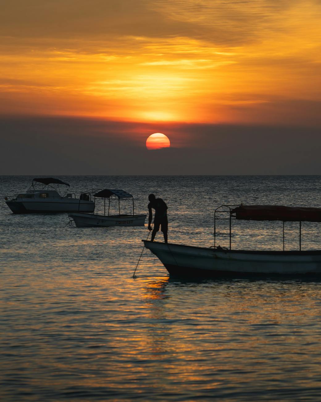 fisherman standing on a boat at sunset